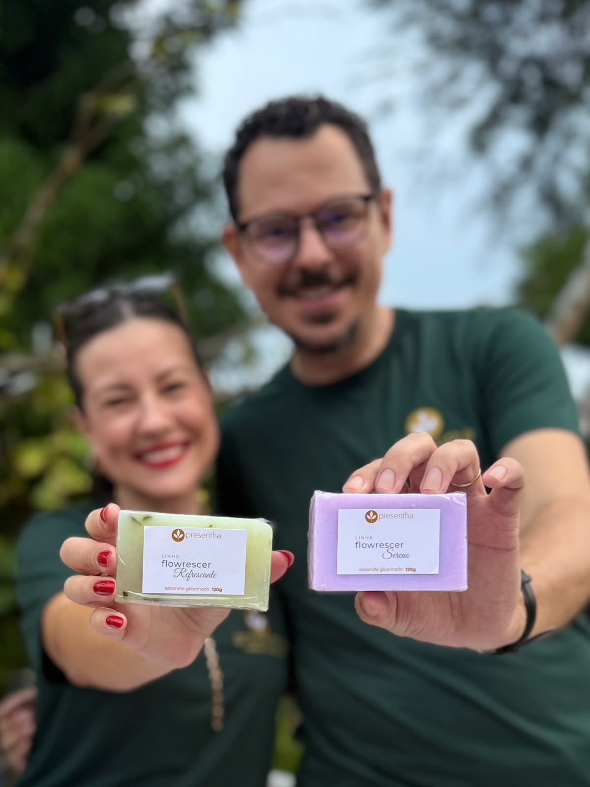 Tiago e Esther apresentando dois sabonetes artesanais da Presentha, nas cores verde e lilás.